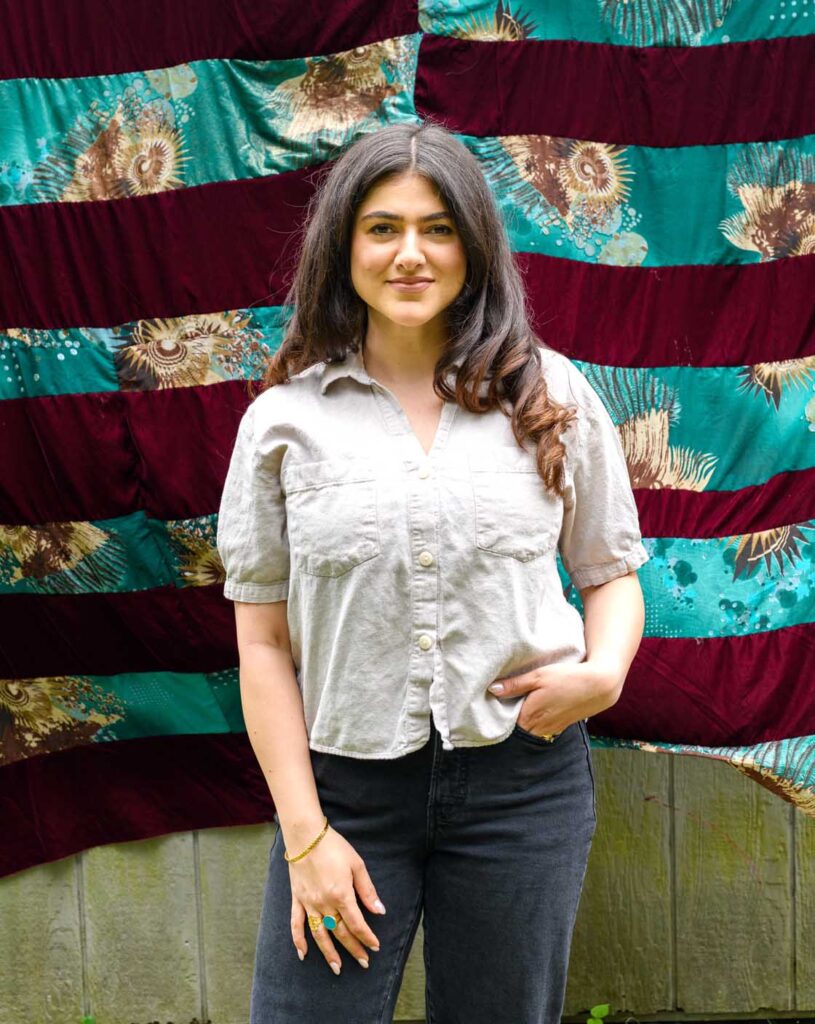 Woman standing in front of her textile art.